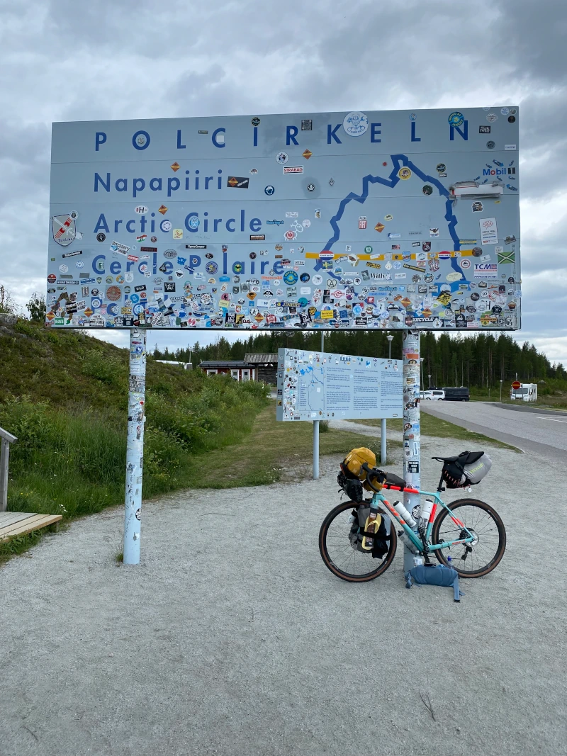 My bike resting against a big billboard that indicates the start and end of the polar circle